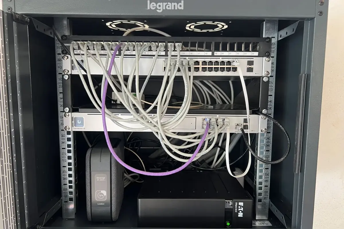 Baie réseau Legrand avec panneau de brassage, équipements Ubiquiti et câblage structuré.
